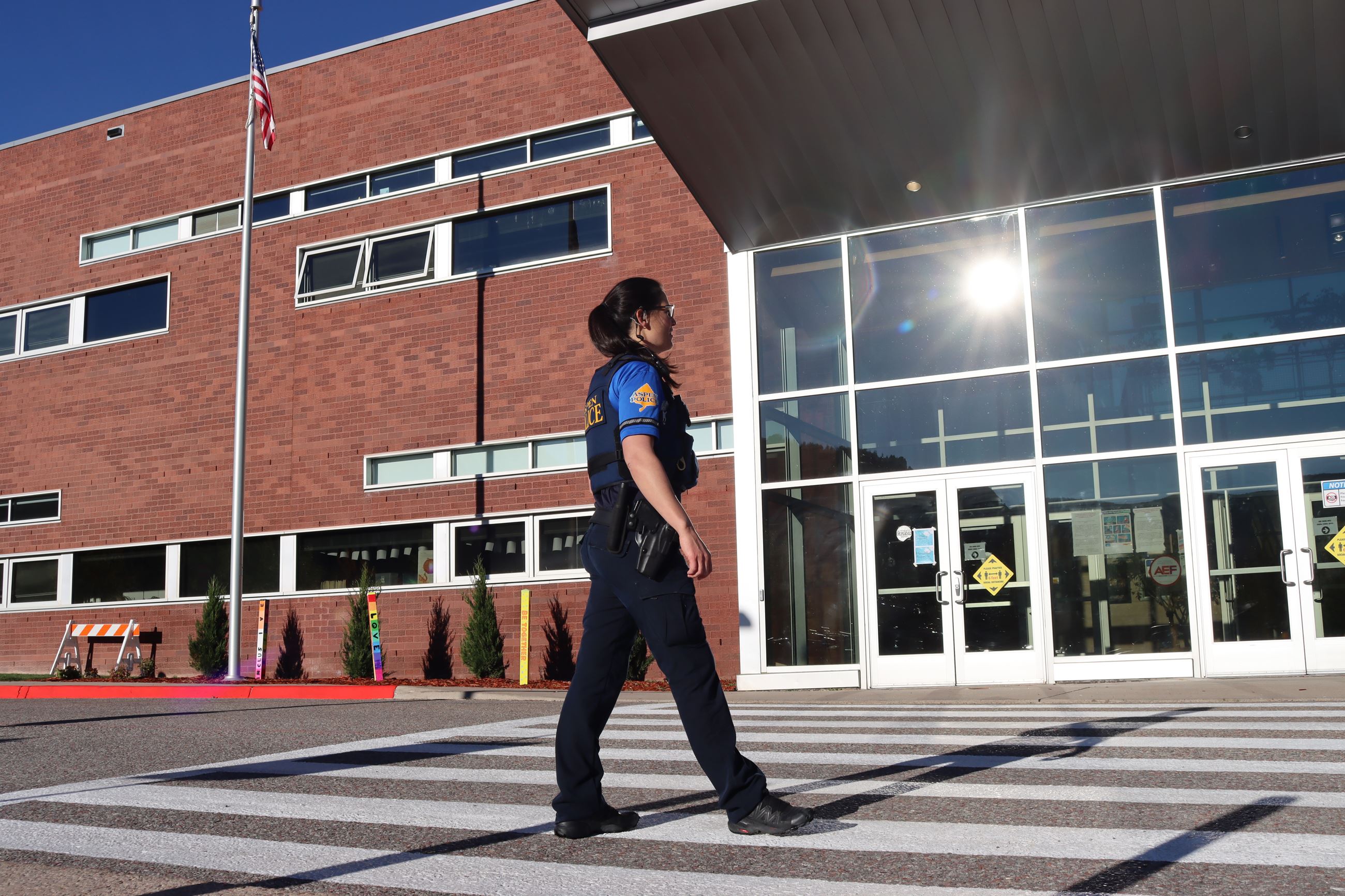 Female police officer posing with back to camera outside school