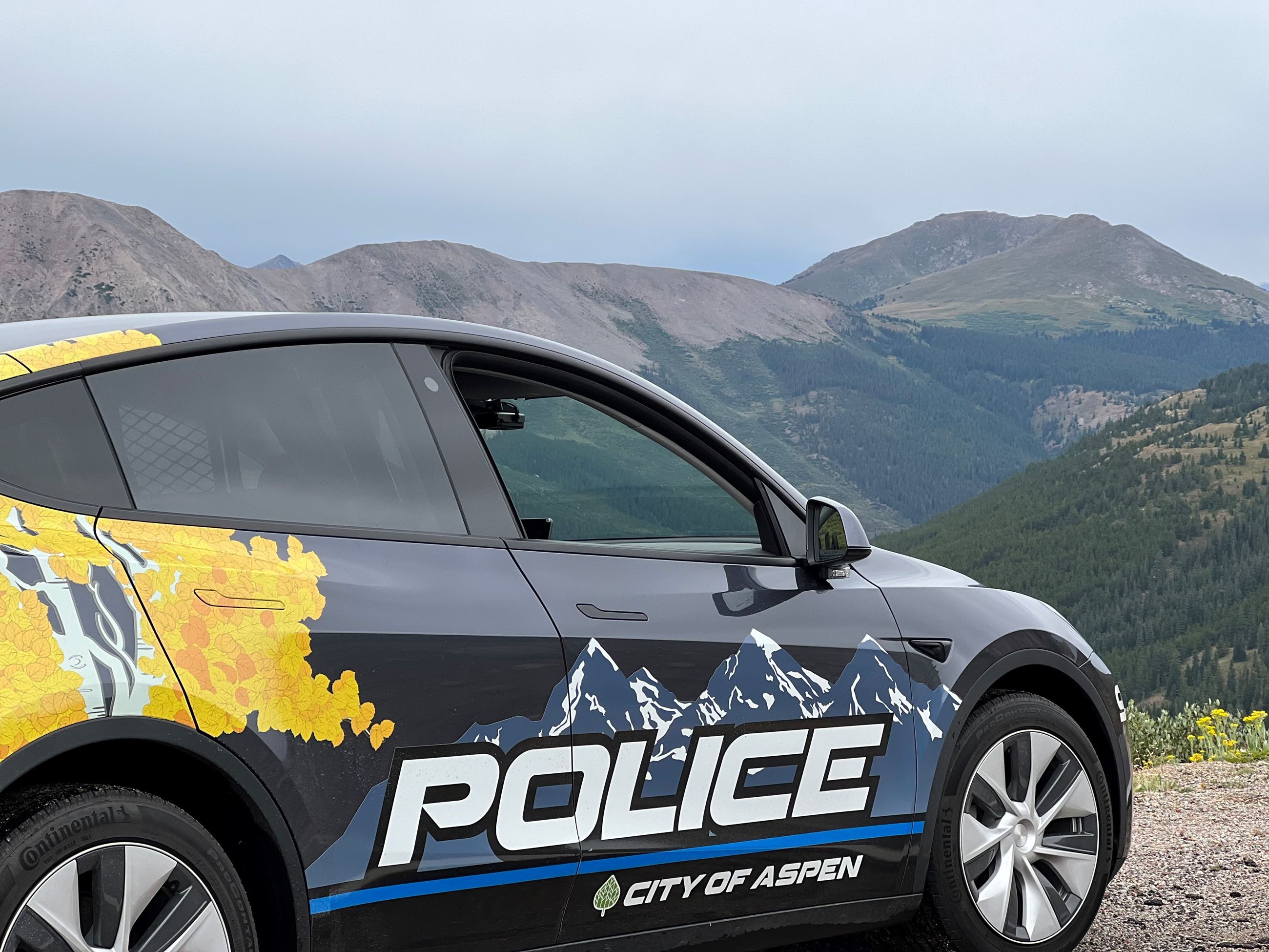 Tesla SUV with Aspen Police Department logo on side photographed infront of mountains